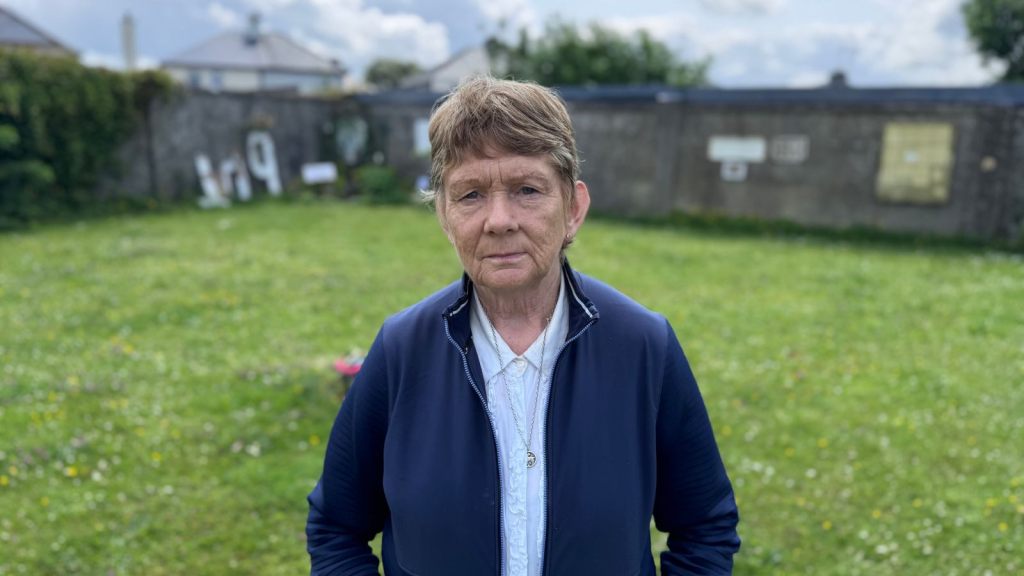 Catherine Corless, une enseignante à la retraite devenue historienne locale, debout près du site de masse.