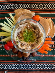 Houmous avec za'atar entouré de tranches de pita et de carottes, de céleri et de tomates